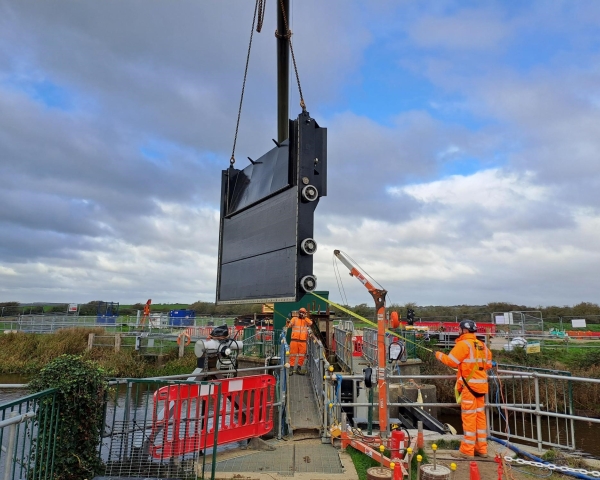 two people on a construction site lifting a part of a gate into place.