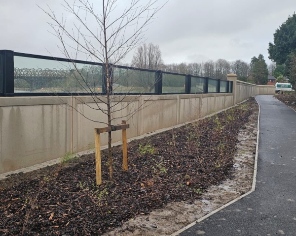Brick wall with glass panels on top alongside a river