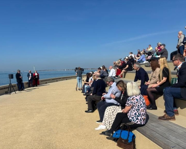 People sat on seafront promenade with blue skies
