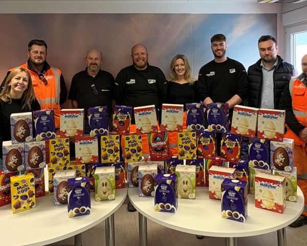 Men and women stood behind a table in an office with Easter eggs on the table