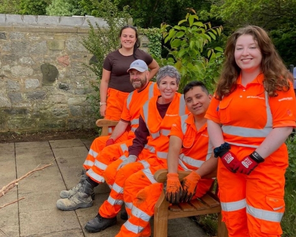 Team in orange PPE sat on a bench in a community garden in Sunderland
