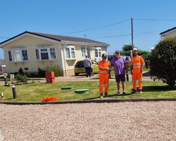 People stood on grass outside a carpark.
