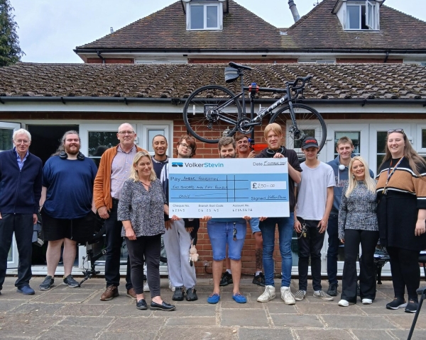 Picture of a group of people stood around a prop check and holding a bike above their heads.