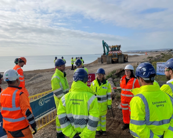 People in high vis stood on a beach.