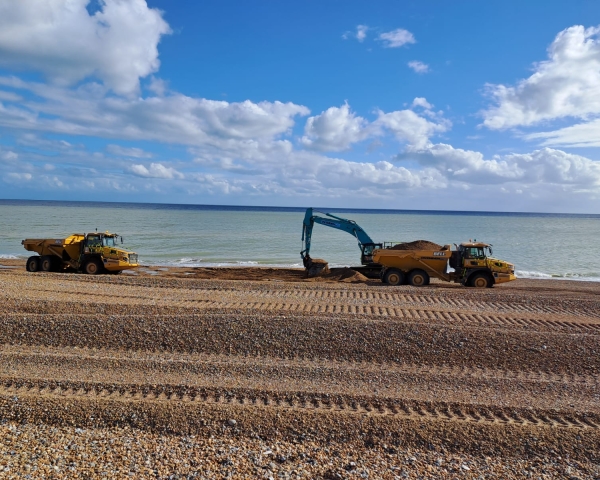 Picture of an excavator on a shingle beach.