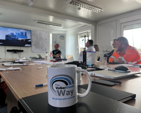 Picture of a Safety Ripple mug with people sat around a desk.