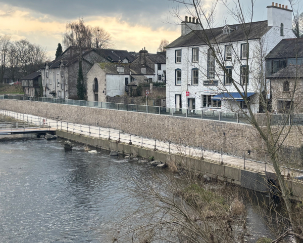 River showing glass panel flood wall looking onto housing