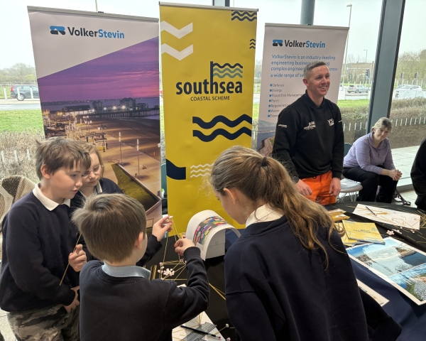 School children looking at information on a stand with banners beg=hind a table