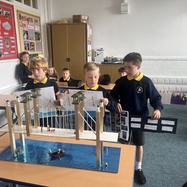Primary school children holding up a model bridge.
