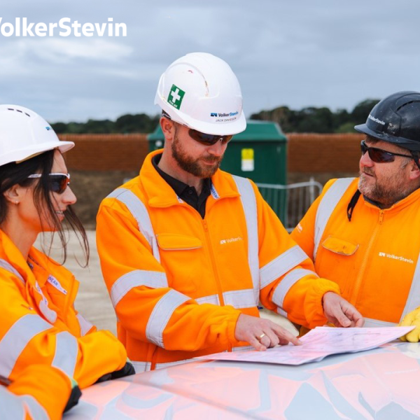 Three people looking at a book smiling