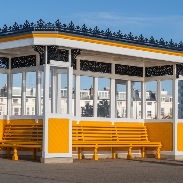 Covered shelter with bench seating around it painted in yellow
