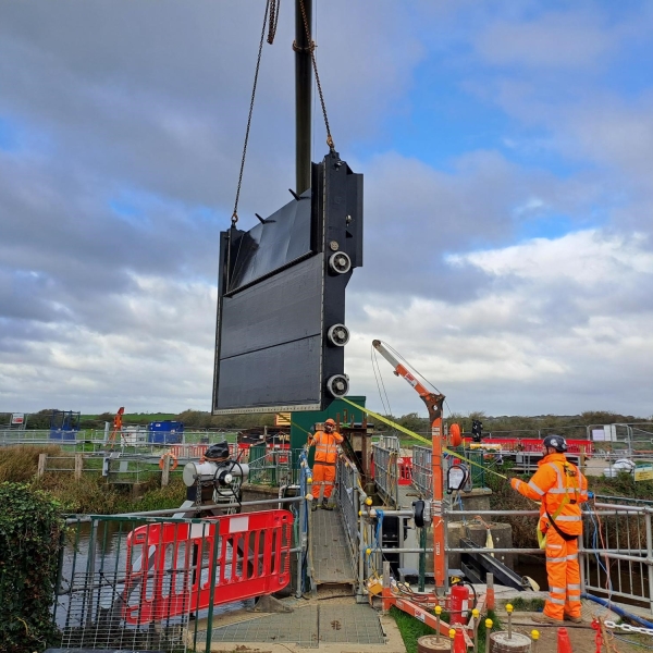 two people on a construction site lifting a part of a gate into place.