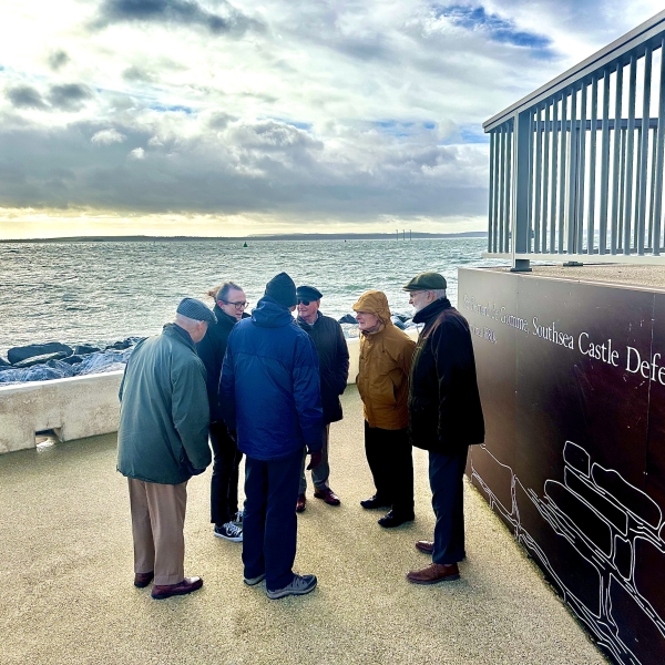 A group of male retired engineers stood by fencing on Southsea promenade