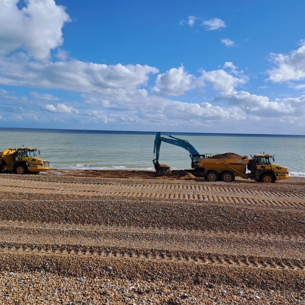 Picture of an excavator on a shingle beach.