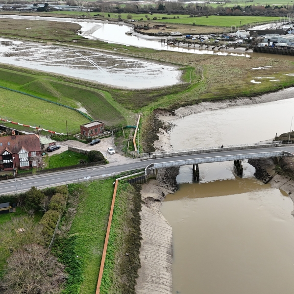 River running under a bridge next to fields.