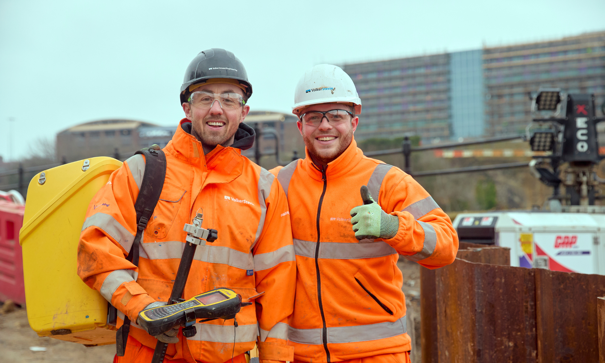 Tow men in orange hi-vis workwear on a construction site