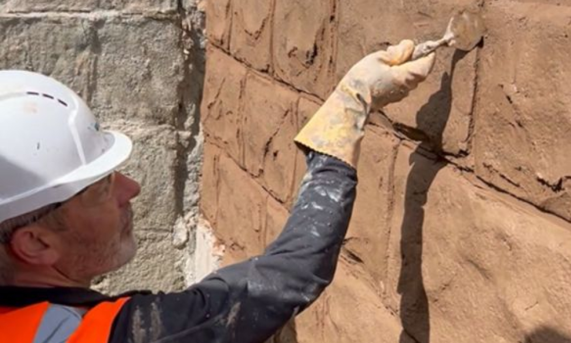 Man carving a concrete wall.