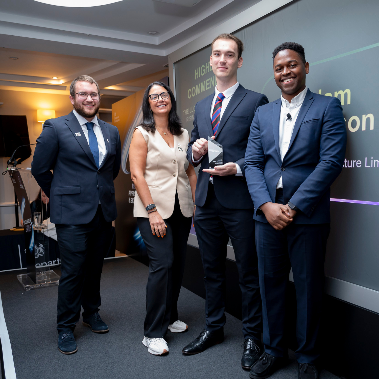 Group of three men and one women presenting an award