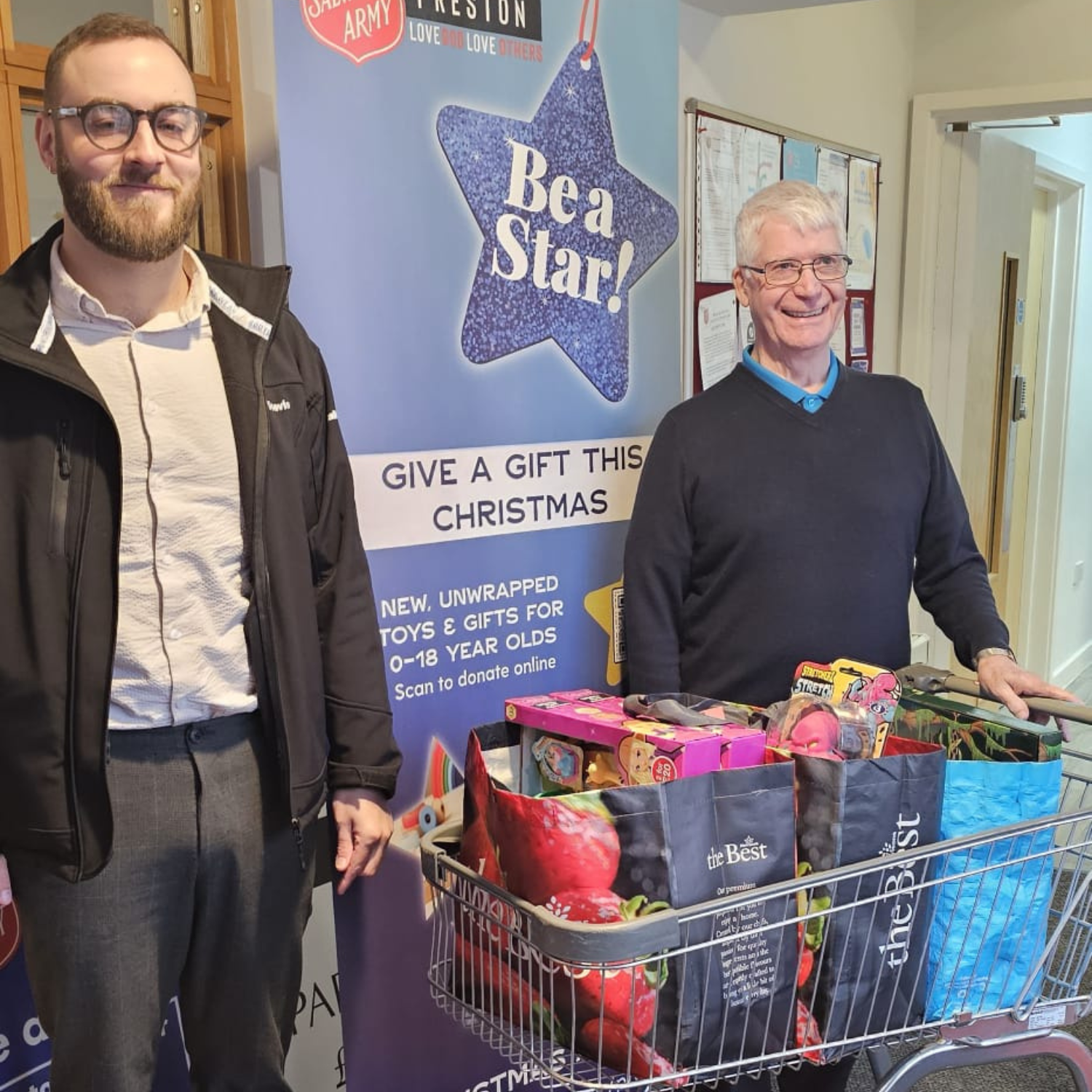 Two men stood by a trolley with food donations