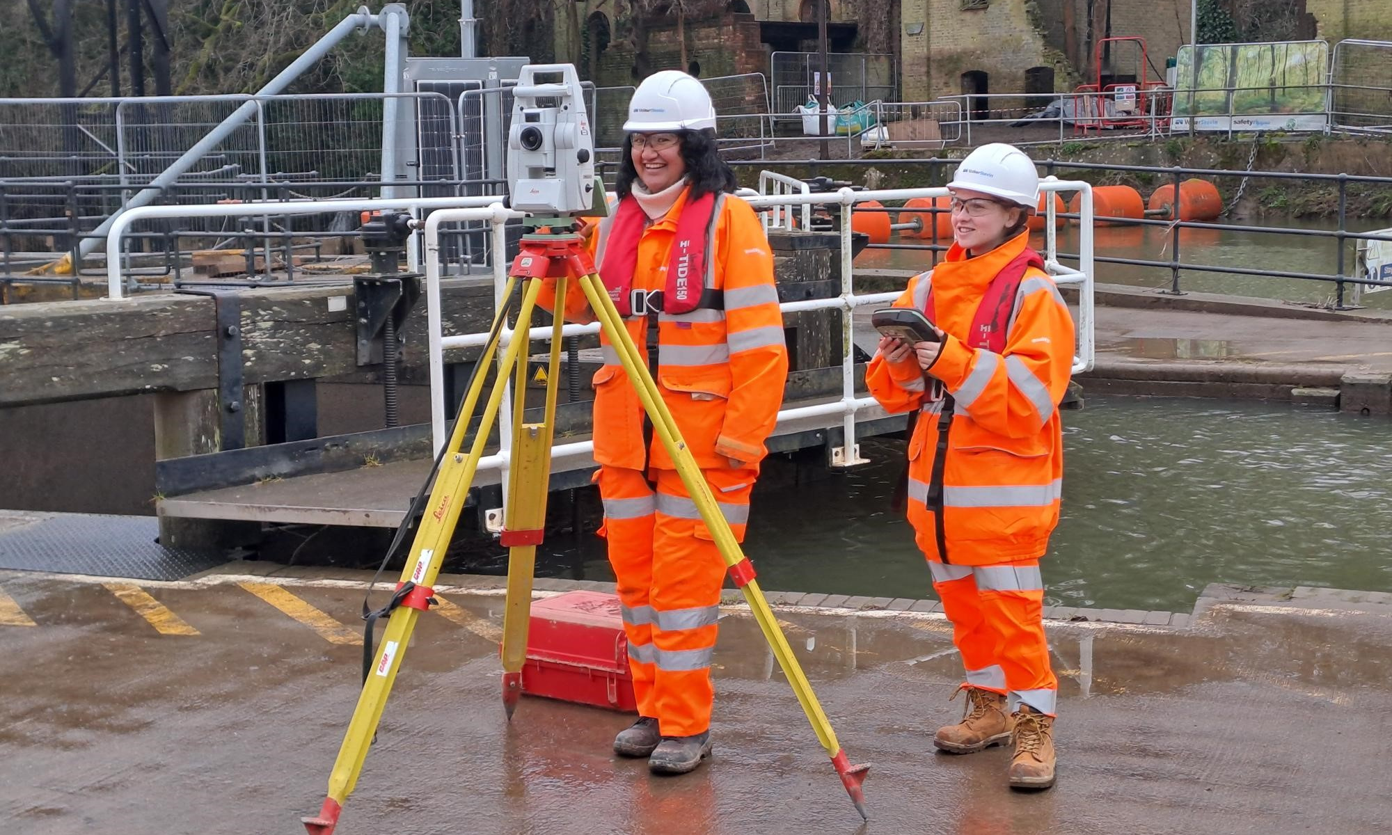 Two people smiling in orange highvis.
