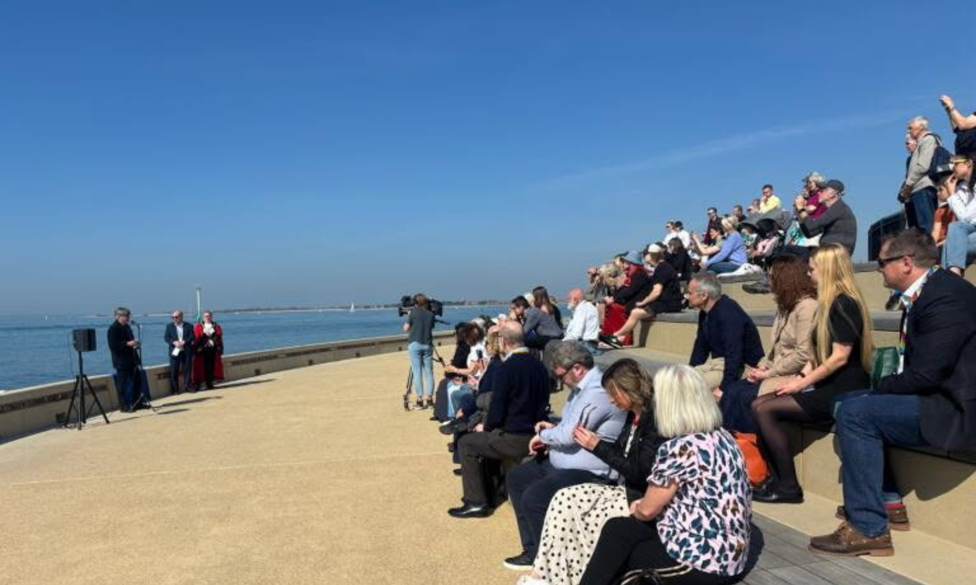 People sat on seafront promenade with blue skies