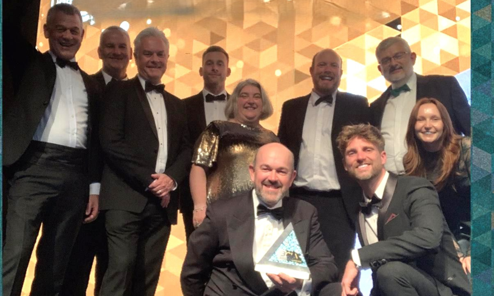 Group photo of men and women on a stage in black tie accepting an award
