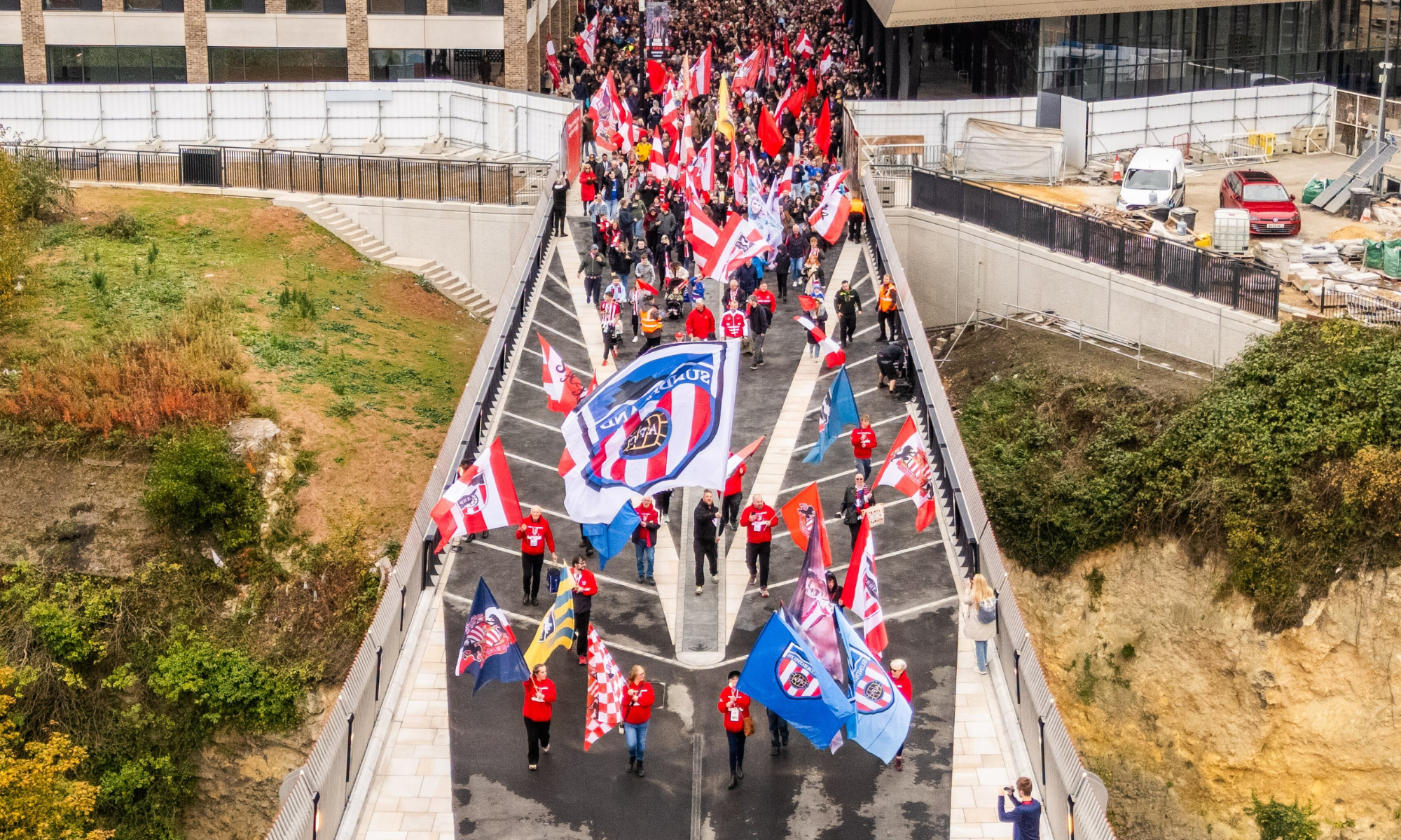 Keel Crossing opening - People walking across the bridge with red and white flags and blue and red flags