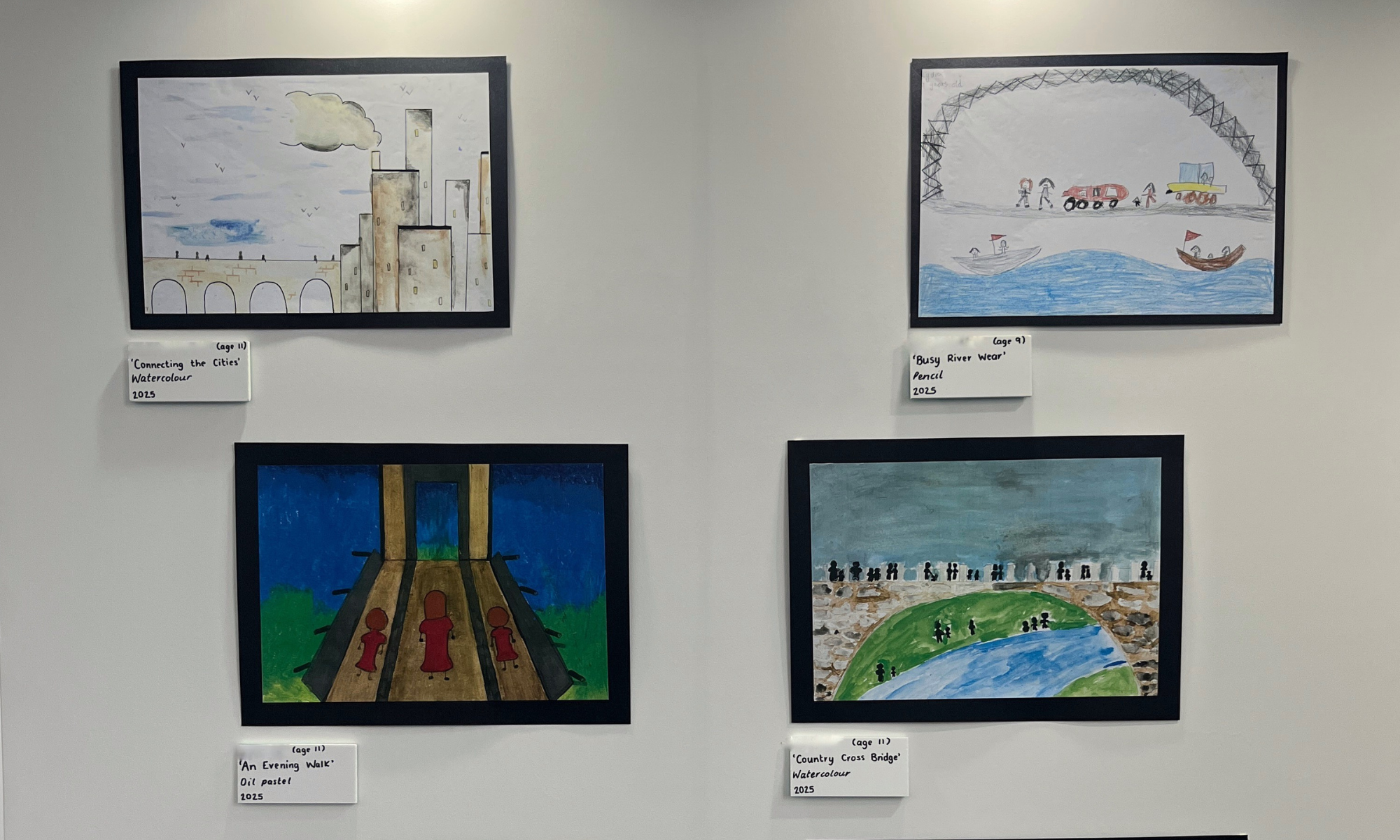 photo of children's drawings of bridges framed on a white wall