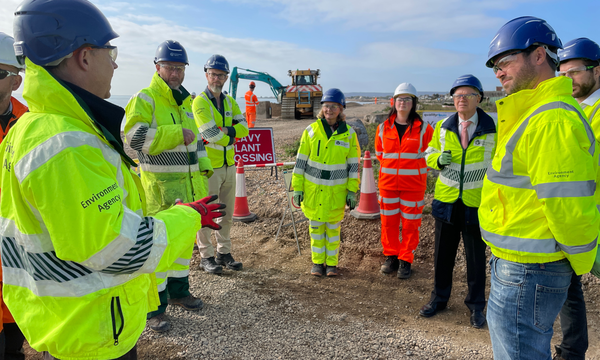 People in high vis stood on a beach.