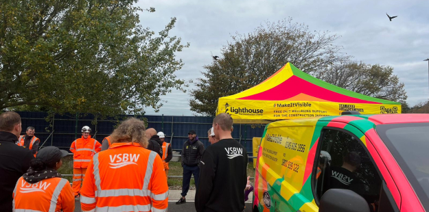 Group of construction workers in hi-vis workwear stood in a car park