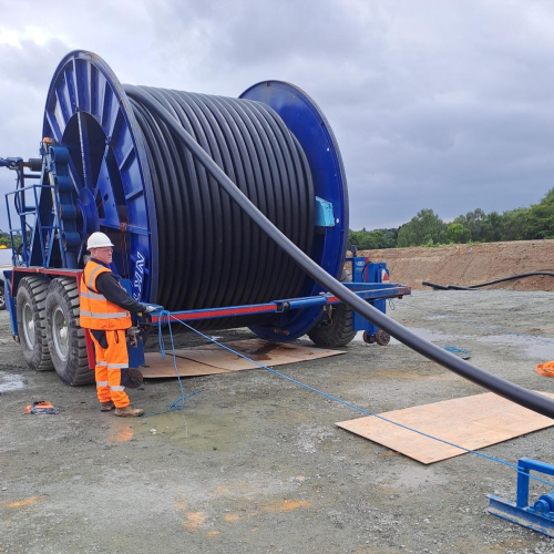 Cable drum with man feeding the cable of it.