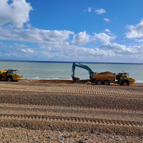 Picture of an excavator on a shingle beach.