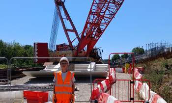 Student on site stood in front of a crane.