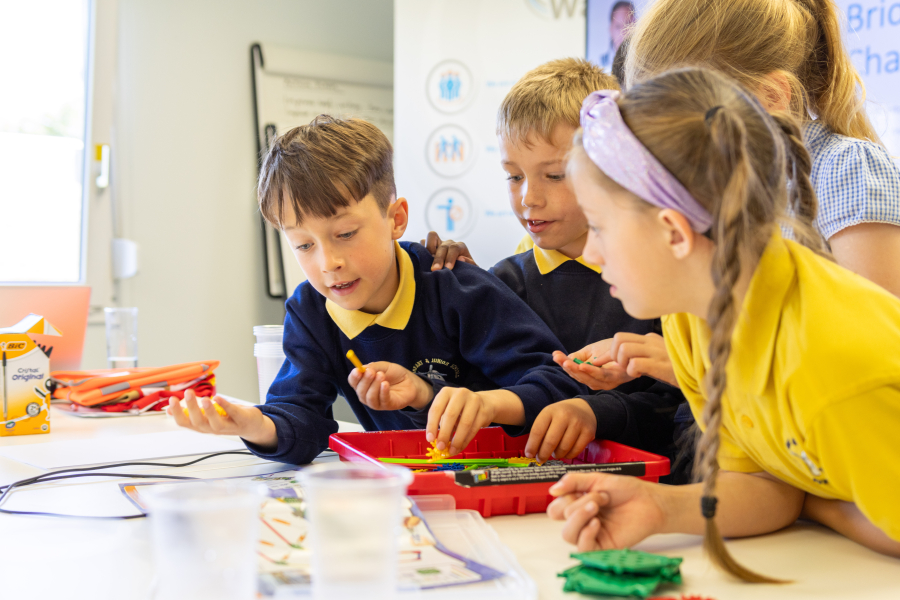 Two boys and two girls at a desk designing a model bridge