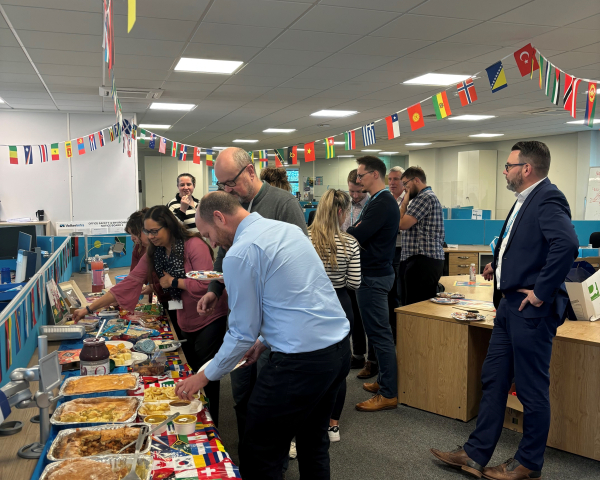 People stood around a buffet table with flags hanging above.