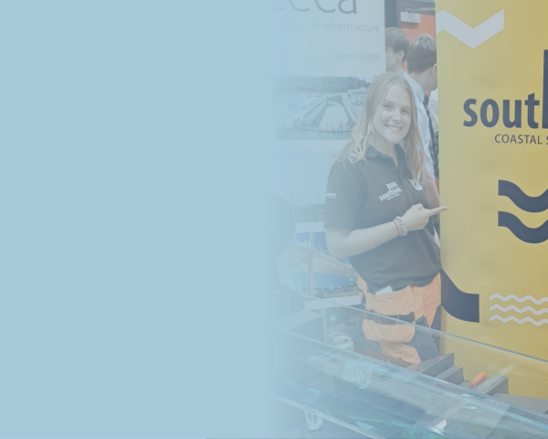 Two women stood alongside a large free standing banner with yellow and blue 