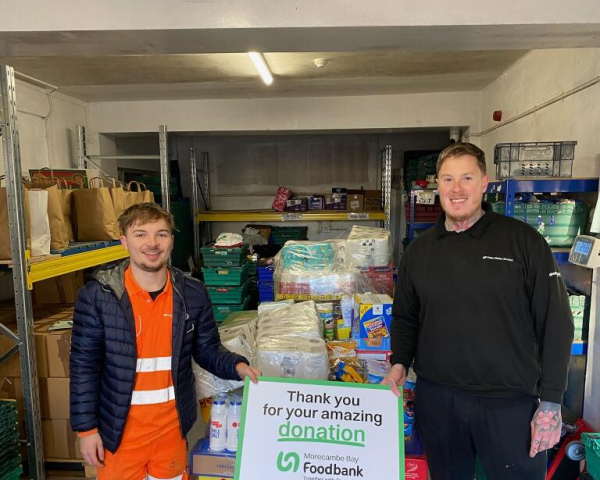 two men stood by crate with food donations on