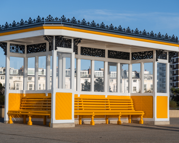 Covered shelter with bench seating around it painted in yellow