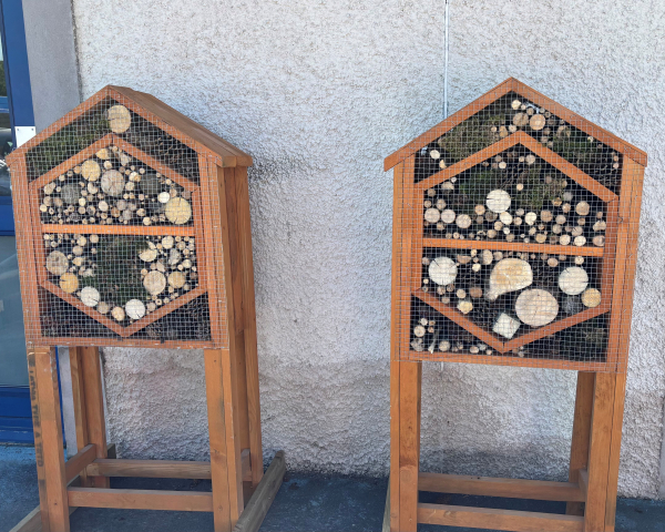 Two bug houses made of wood with logs and twigs inside