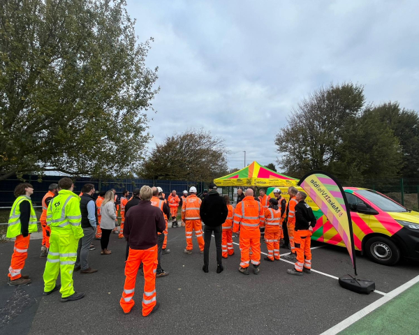 Group of construction workers in hi-vis workwear stood in a group in a car park