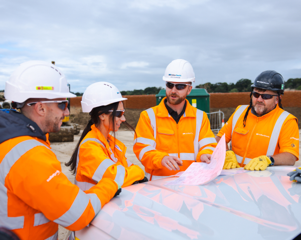 People in high vis stood around a drawing.