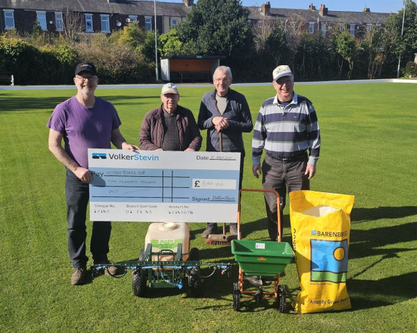 Four men stood on a bowling green holding a large cheque