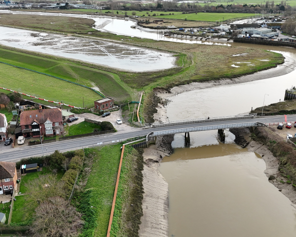 River running under a bridge next to fields.