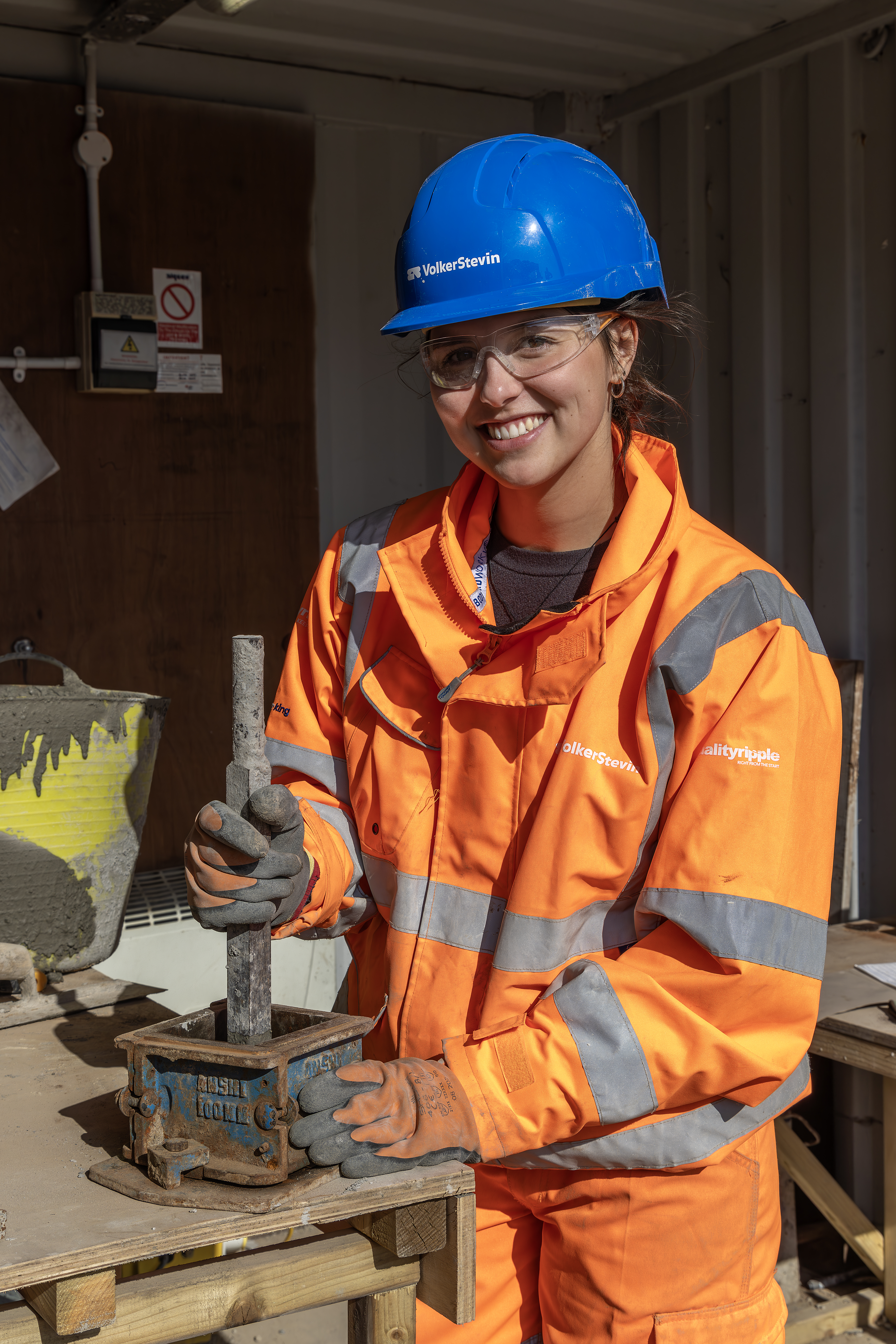 Women in orange hi-vis workwear stood by a workbench