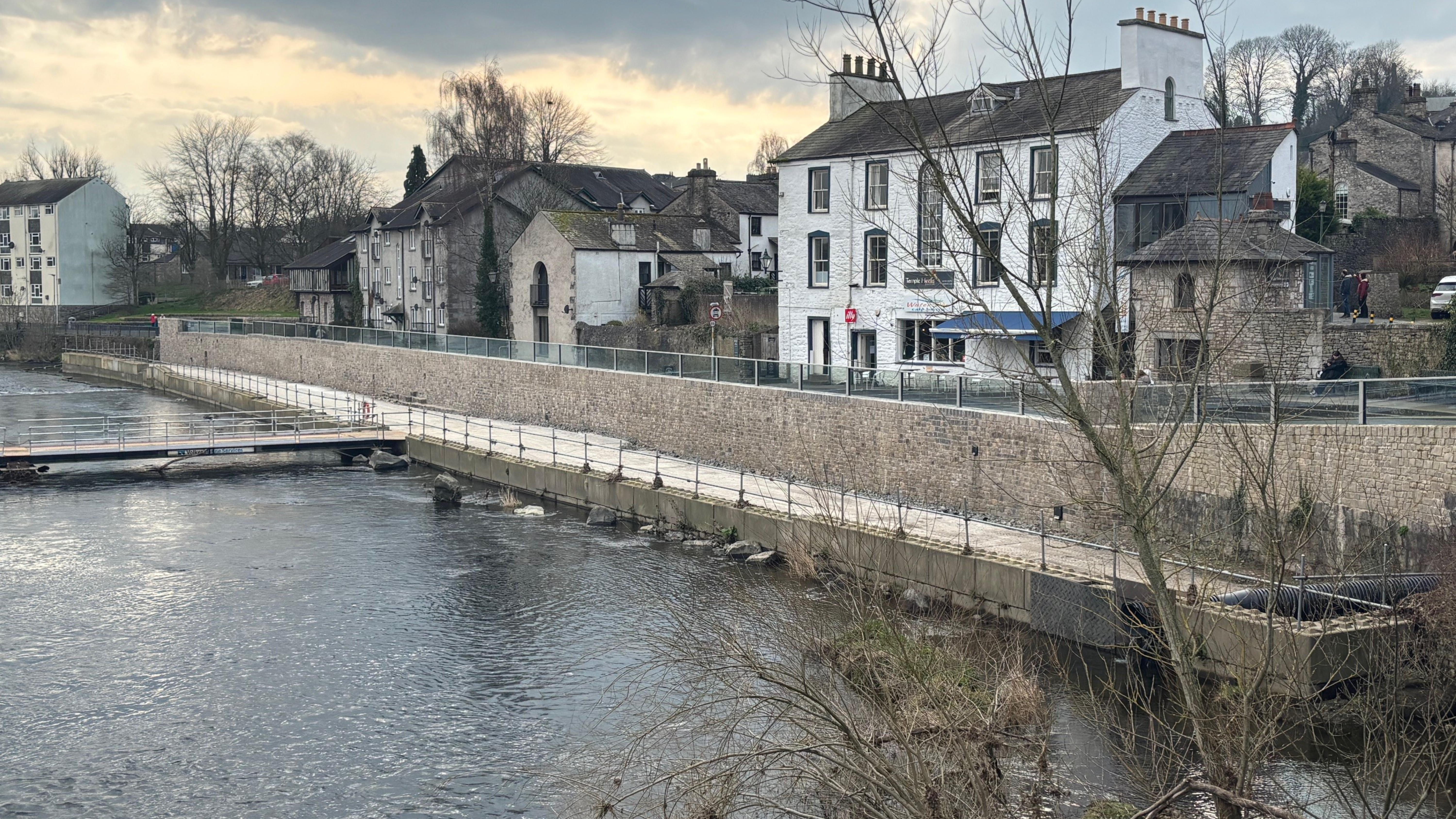River showing glass panel flood wall looking onto housing